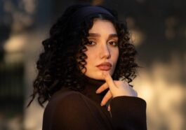 A woman with curly hair wearing a dark turtleneck