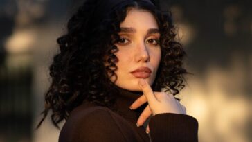 A woman with curly hair wearing a dark turtleneck
