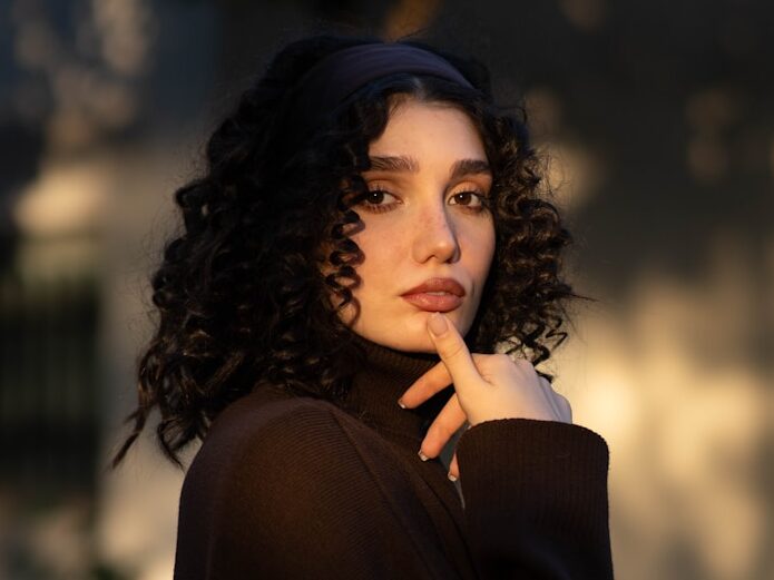 A woman with curly hair wearing a dark turtleneck