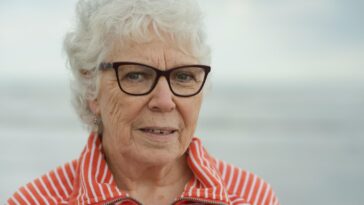 An elderly woman smiles at the camera.