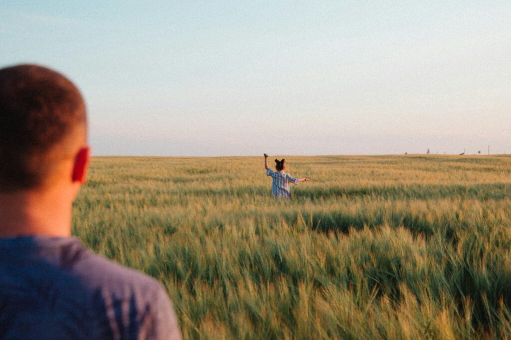 person in gray shirt standing on green grass field during daytime