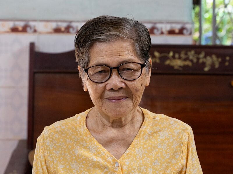 an elderly woman sitting on a bench in a church