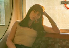 woman in beige tank top and blue denim jeans sitting on gray and brown chair
