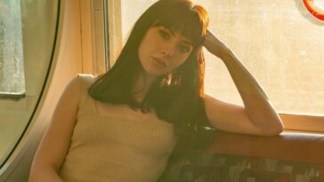 woman in beige tank top and blue denim jeans sitting on gray and brown chair