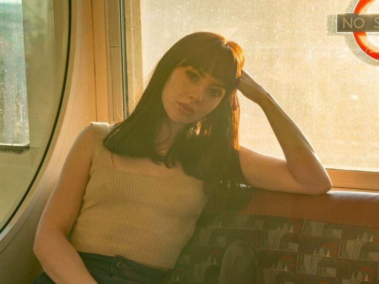 woman in beige tank top and blue denim jeans sitting on gray and brown chair
