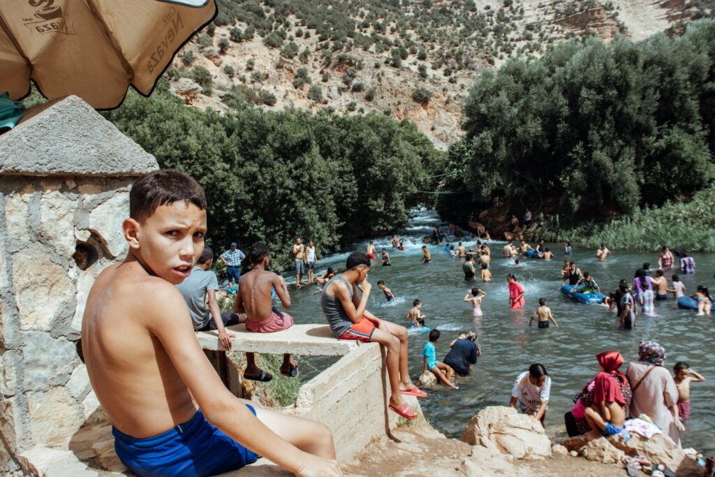 A young boy sitting on a wall next to a body of water
