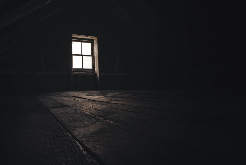 a dark room with a window and a wooden floor