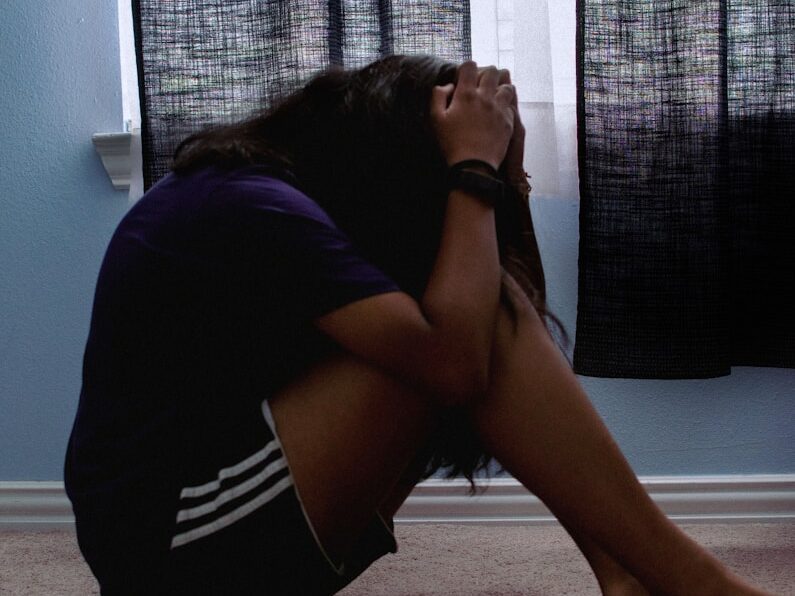 a woman sitting on the floor with her head in her hands