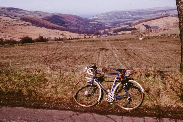 A bicycle parked on a grassy hill overlooking a valley.