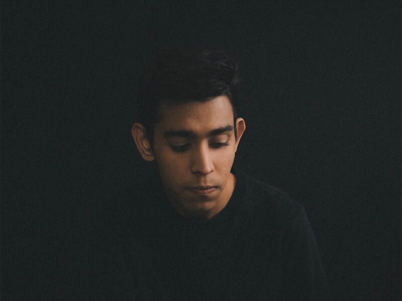 man wearing black long-sleeved shirt sitting while looking down