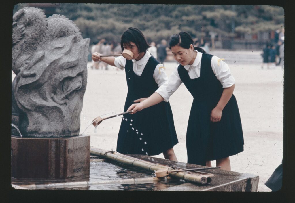 Two young girls are playing with a water fountain