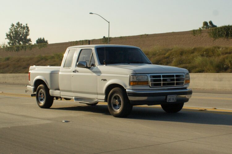 White pickup truck driving on a highway.