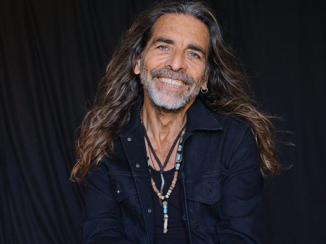 a man with long hair sitting on the ground