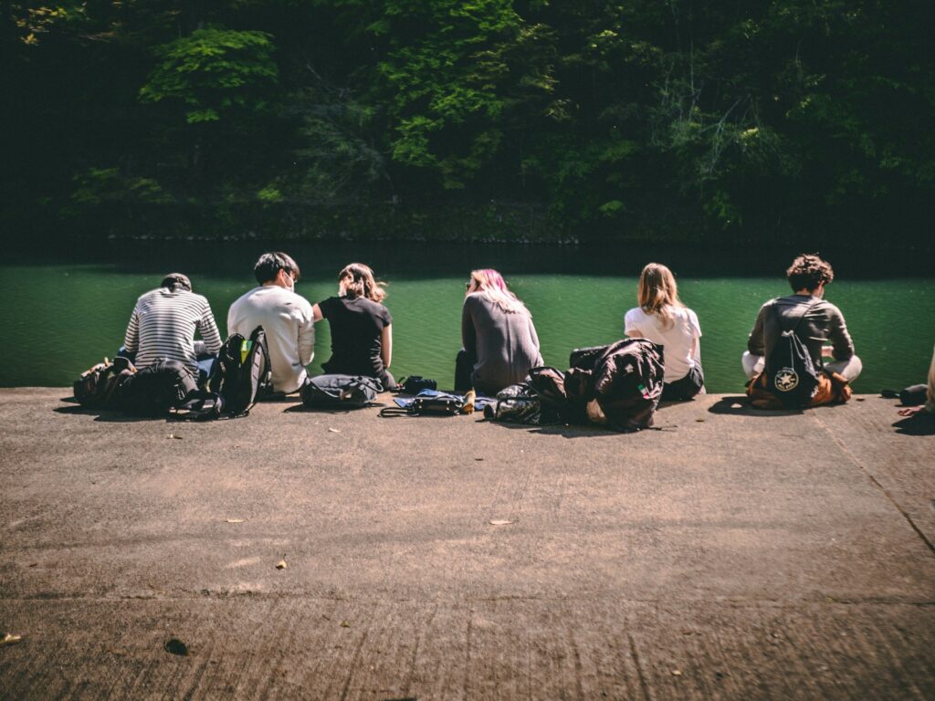 group of people sitting on gray asphalt road during daytime