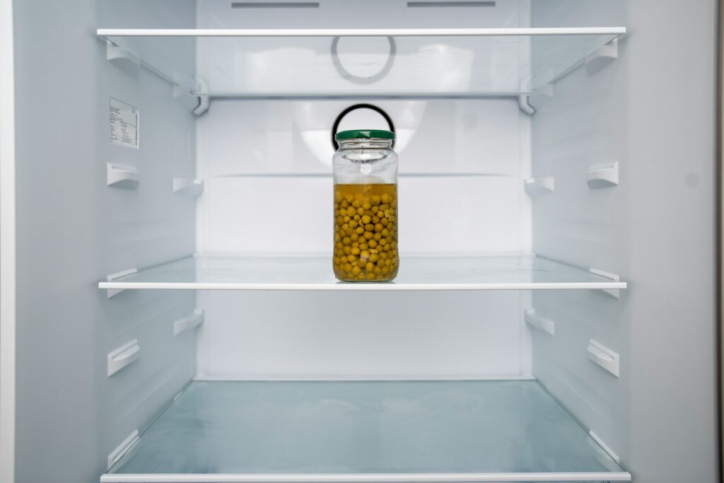 An open refrigerator with a jar of mustard in it