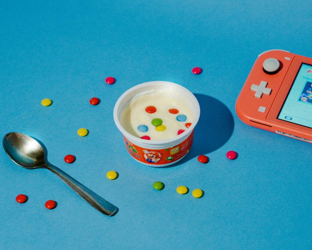 a cup of yogurt and a spoon on a blue surface