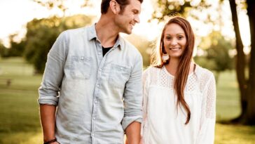 man holding hand of woman standing near tree