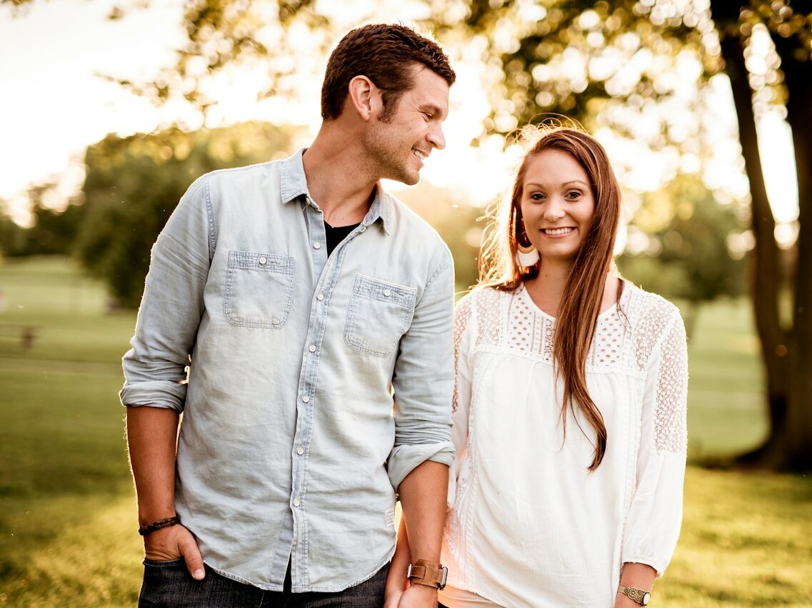 man holding hand of woman standing near tree