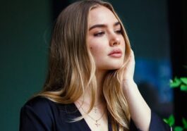 a woman leaning against a wall with her hand on her head
