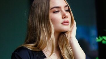 a woman leaning against a wall with her hand on her head