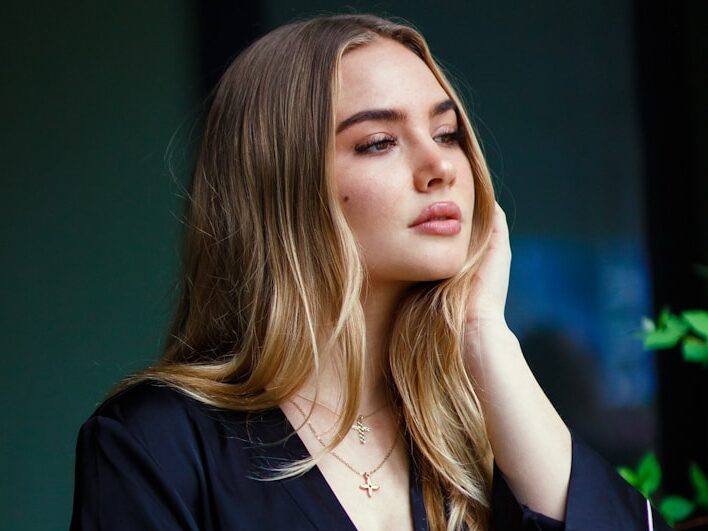 a woman leaning against a wall with her hand on her head