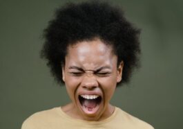 African American woman with afro hair expressing intense emotion by shouting.