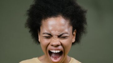 African American woman with afro hair expressing intense emotion by shouting.