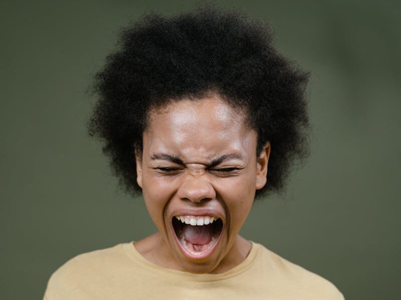 African American woman with afro hair expressing intense emotion by shouting.
