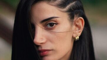 a woman with long black hair wearing a white shirt