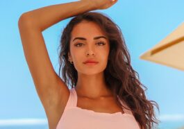 woman in white spaghetti strap top holding her hair