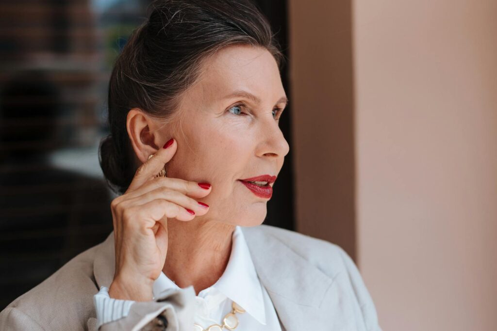 Portrait of an elegant senior woman with red lips and manicured nails, embodying grace and confidence.