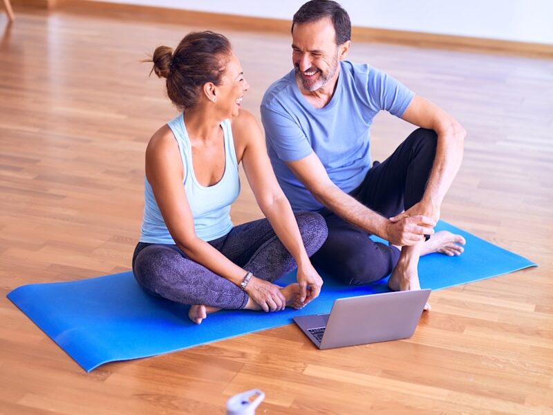 man in white tank top and gray pants sitting on blue yoga mat