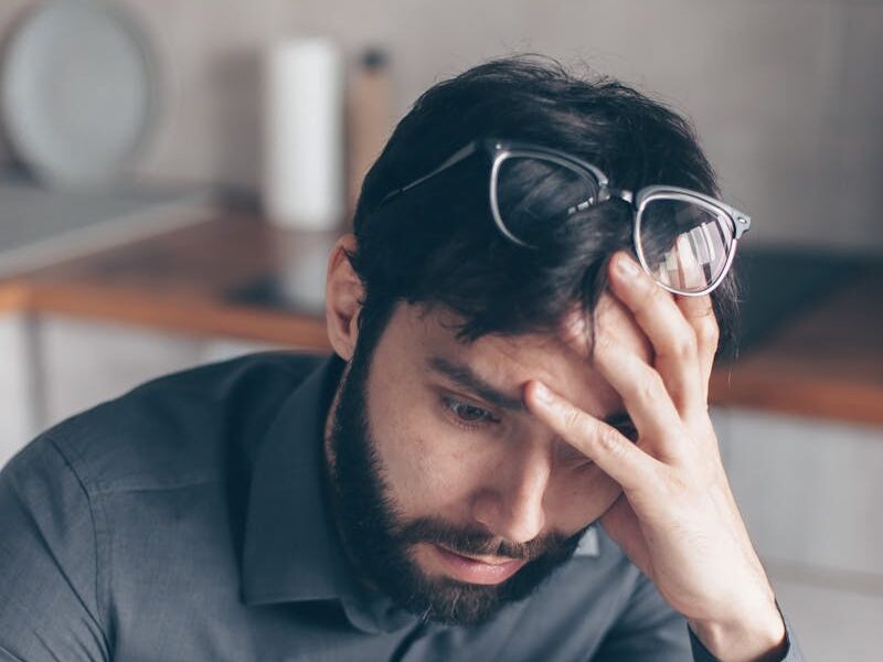 Man with eyeglasses on head looks worried as he reads paperwork, expressing concern.