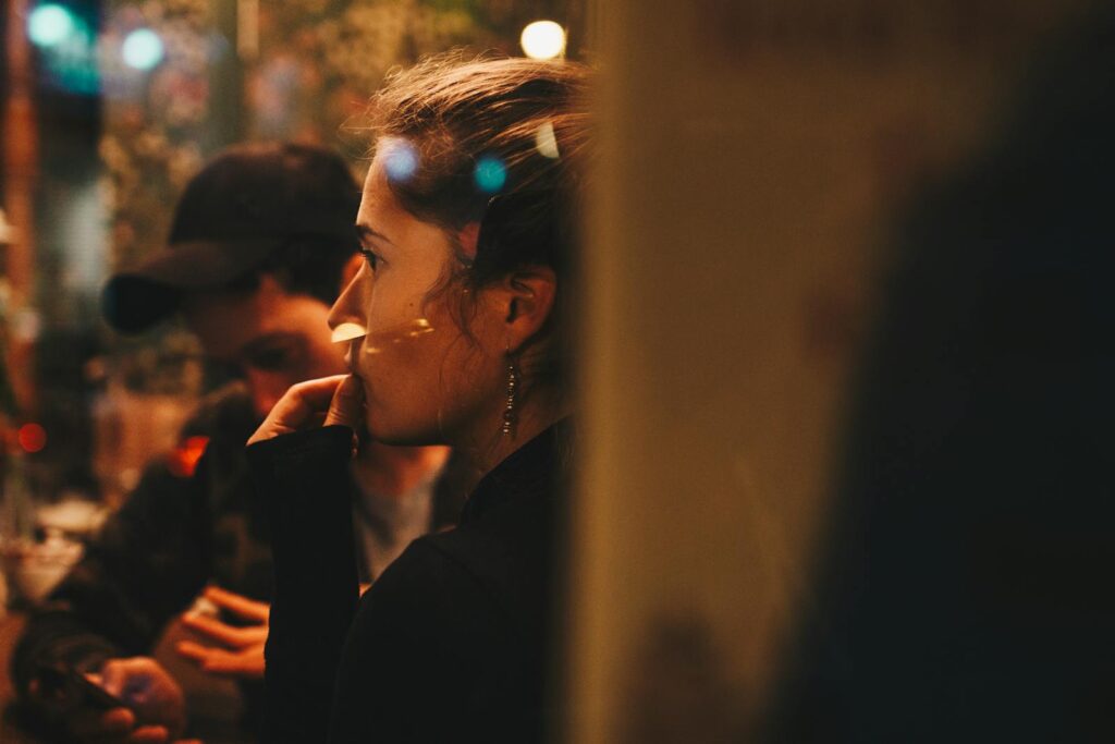 A thoughtful woman sits in a softly lit cafe, immersed in evening ambiance.