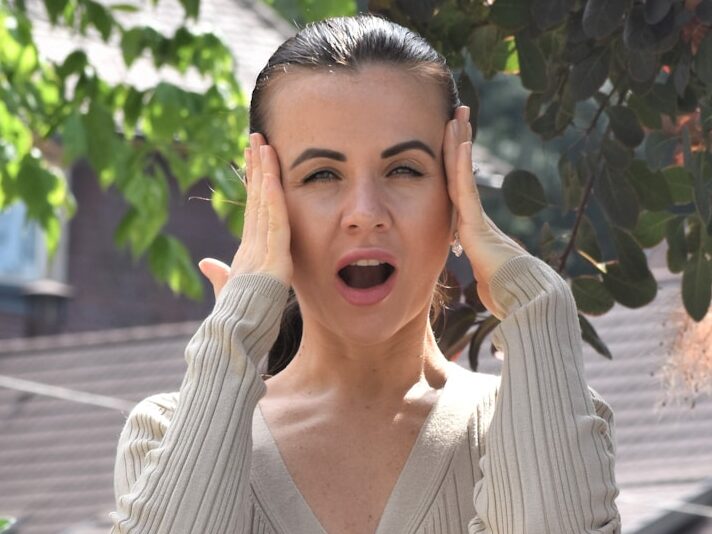 a woman holding her hands up to her ears