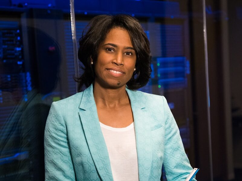 woman in blue blazer standing beside glass wall